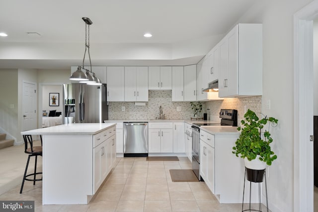 kitchen featuring tasteful backsplash, appliances with stainless steel finishes, under cabinet range hood, a kitchen bar, and recessed lighting