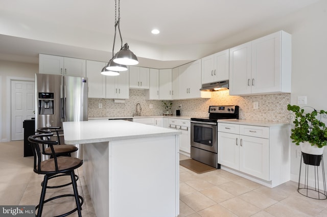 kitchen featuring a breakfast bar area, stainless steel appliances, under cabinet range hood, a sink, and a center island