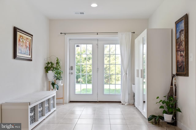 doorway to outside featuring light tile patterned floors, visible vents, a wealth of natural light, and baseboards