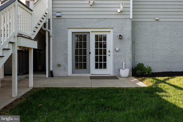 doorway to property with brick siding and a lawn