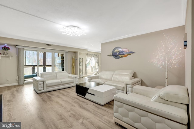 living room with crown molding, wood finished floors, visible vents, and baseboards