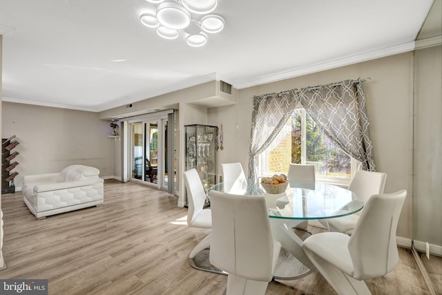 dining room with visible vents, baseboards, ornamental molding, light wood-style flooring, and a notable chandelier