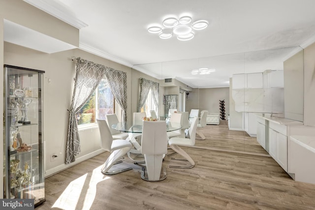 dining area with crown molding, light wood-style flooring, and visible vents