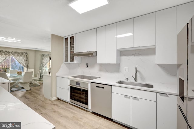 kitchen featuring under cabinet range hood, a sink, stainless steel oven, black electric stovetop, and dishwasher