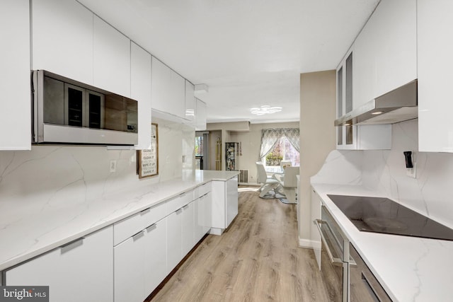 kitchen featuring black electric cooktop, extractor fan, white cabinets, and decorative backsplash