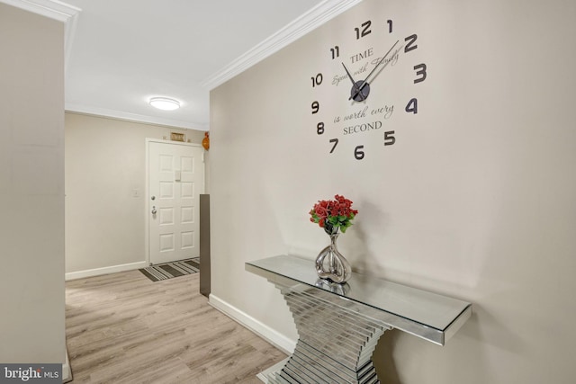 corridor featuring light wood-style flooring, baseboards, and ornamental molding