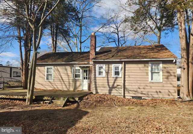 back of property featuring crawl space, a chimney, and fence