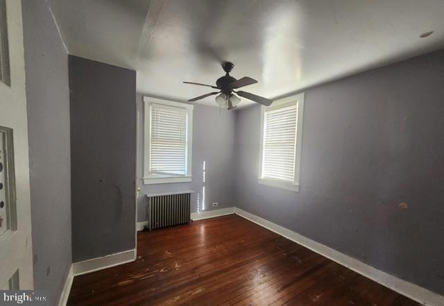 unfurnished room featuring radiator, baseboards, ceiling fan, and wood finished floors