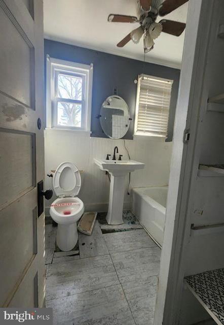 full bath with toilet, a tub to relax in, and ceiling fan