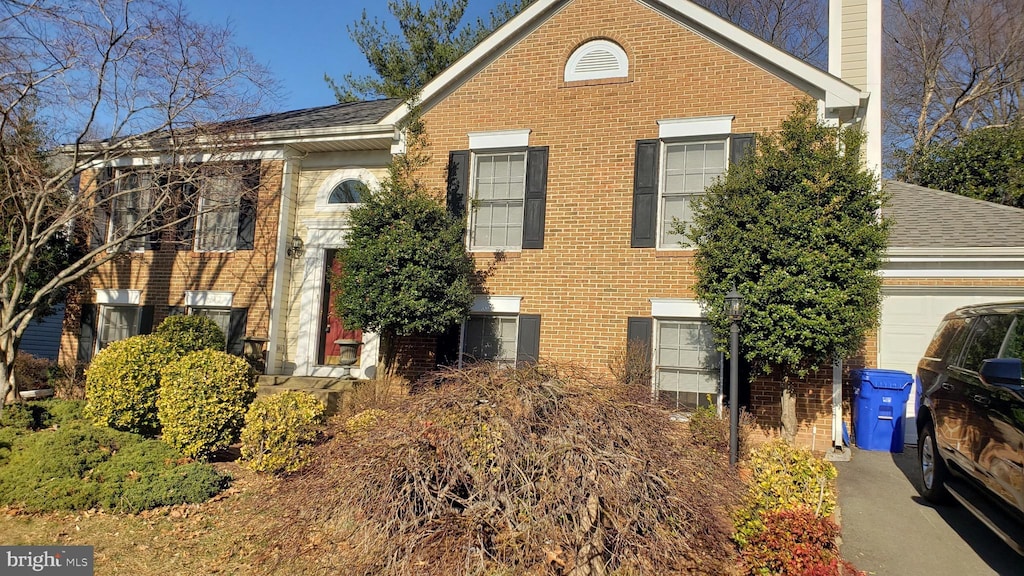 view of side of home featuring a chimney, brick siding, roof with shingles, and an attached garage