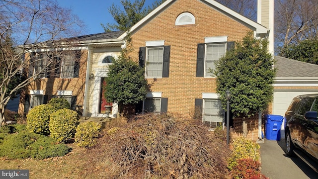 view of side of home featuring a chimney, brick siding, roof with shingles, and an attached garage