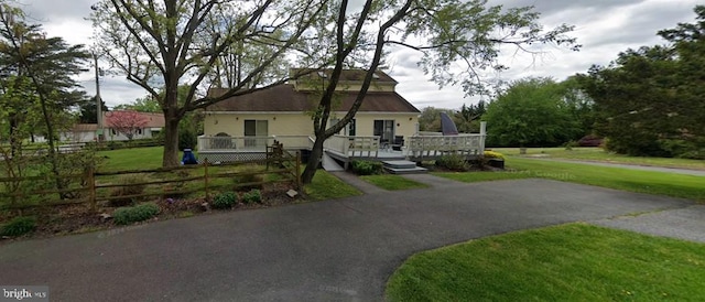 view of front of home with a front lawn, fence, and a wooden deck