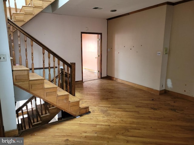 staircase with visible vents, baseboards, and wood finished floors