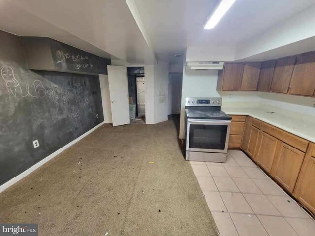 kitchen featuring under cabinet range hood, brown cabinets, stainless steel electric range oven, and light countertops