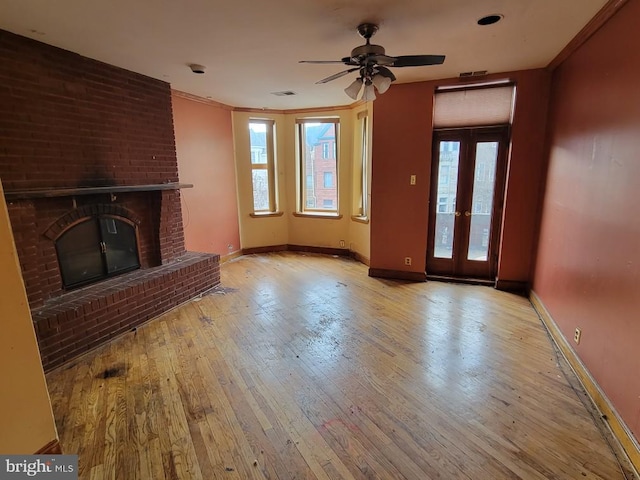 unfurnished living room featuring hardwood / wood-style floors, baseboards, a fireplace, ceiling fan, and crown molding
