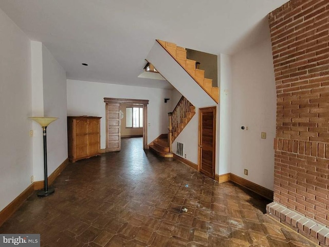 unfurnished living room with stairway, visible vents, baseboards, and dark floors