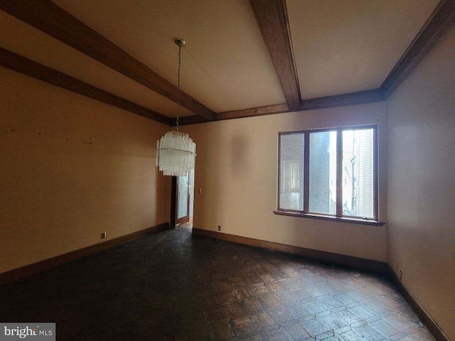 spare room with a chandelier, beamed ceiling, and baseboards