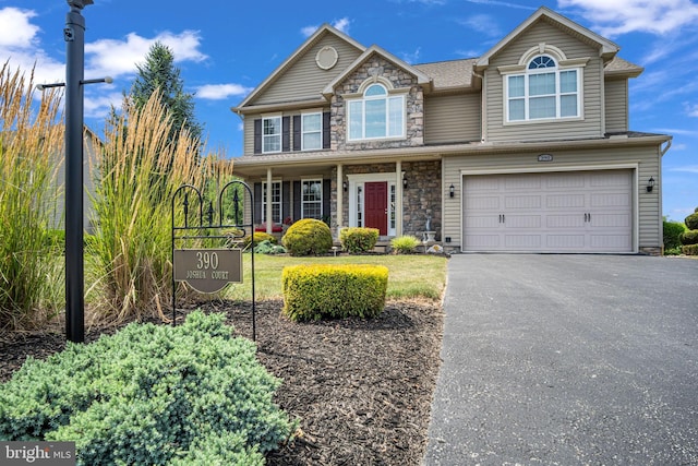 view of front of home featuring an attached garage, stone siding, and driveway