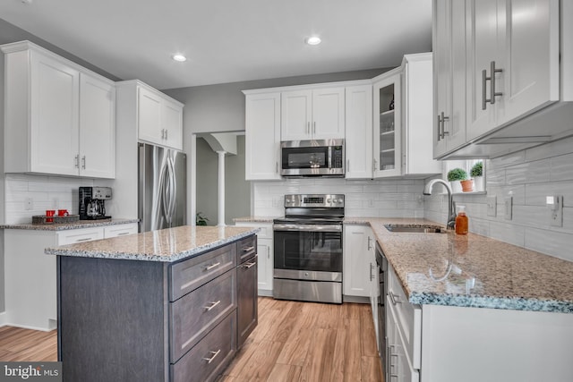 kitchen with a sink, white cabinets, light wood finished floors, and stainless steel appliances