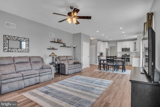 living room with light wood-type flooring, recessed lighting, visible vents, and ceiling fan