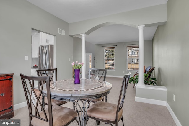 dining space featuring arched walkways, visible vents, baseboards, and ornate columns