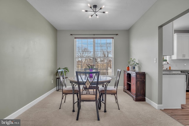 dining room with light colored carpet, baseboards, and a chandelier