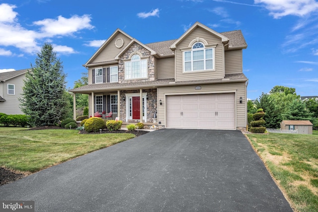 view of front facade featuring a garage, stone siding, a front yard, and driveway