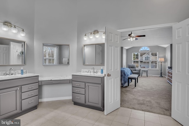 bathroom with two vanities, a sink, ensuite bath, lofted ceiling, and ceiling fan