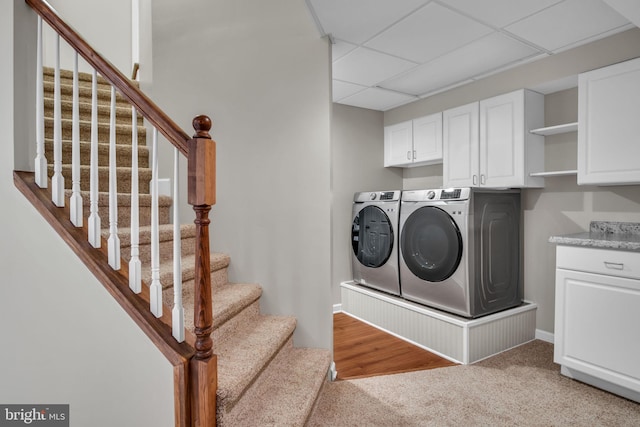 clothes washing area with cabinet space, light colored carpet, and independent washer and dryer