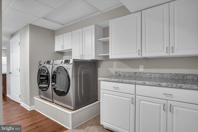 laundry room with baseboards, cabinet space, separate washer and dryer, and wood finished floors