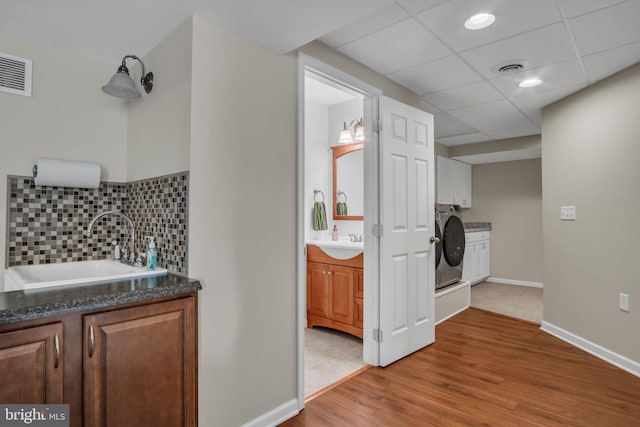 bathroom with decorative backsplash, washer / dryer, wood finished floors, vanity, and a paneled ceiling