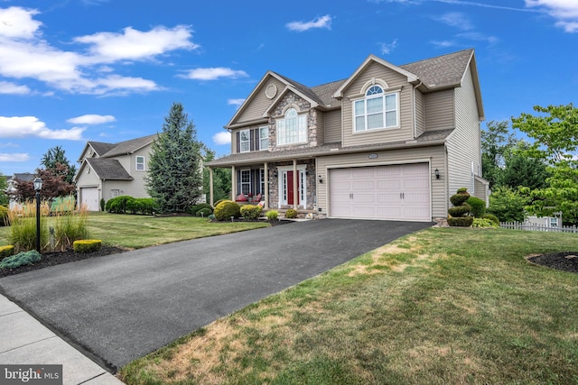 traditional home featuring a front yard, an attached garage, stone siding, and driveway