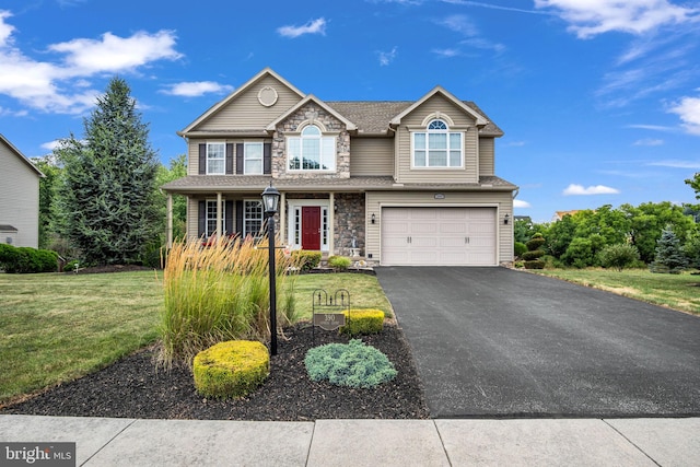 traditional home with stone siding, driveway, a front yard, and a garage