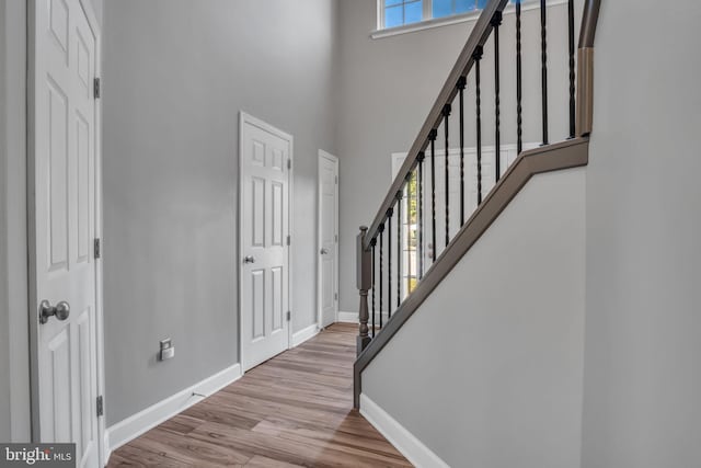 foyer entrance with stairway, baseboards, a towering ceiling, and wood finished floors