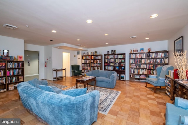 living area featuring visible vents, recessed lighting, and wall of books