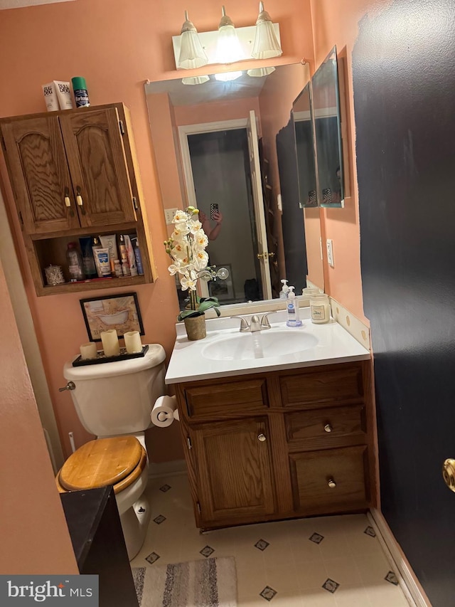 half bath with baseboards, toilet, and vanity