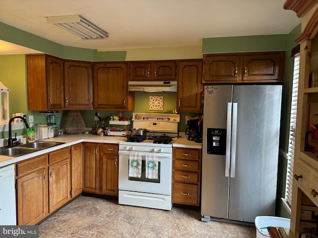 kitchen featuring under cabinet range hood, a sink, white appliances, brown cabinetry, and light countertops