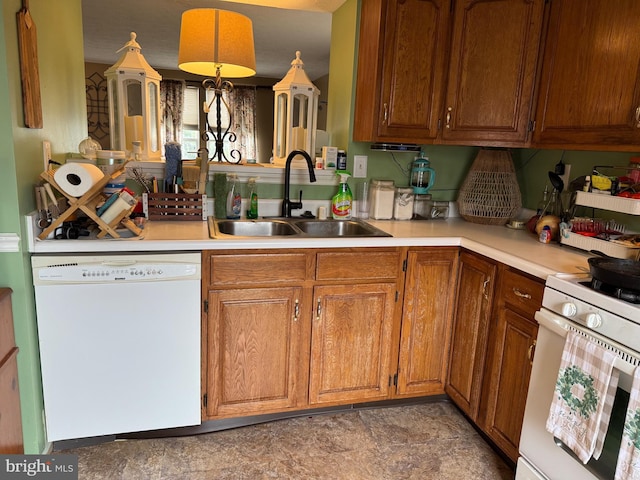 kitchen with white appliances, light countertops, brown cabinets, and a sink