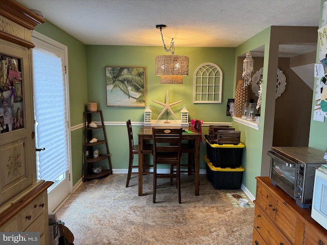 dining space with a toaster, an inviting chandelier, a textured ceiling, and baseboards