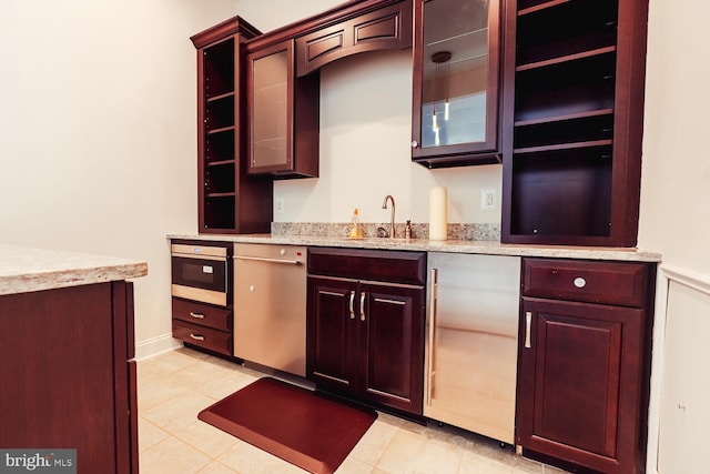 bar featuring stainless steel dishwasher, oven, a sink, wet bar, and light tile patterned flooring