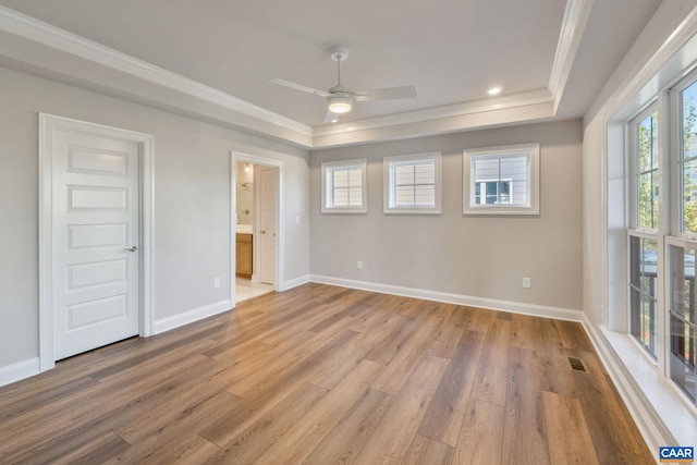 spare room with visible vents, ornamental molding, a ceiling fan, light wood finished floors, and baseboards