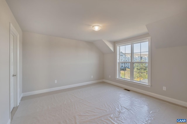 bonus room featuring light carpet, visible vents, baseboards, and vaulted ceiling