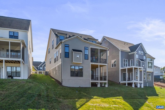 rear view of house featuring central AC unit, a lawn, and a sunroom