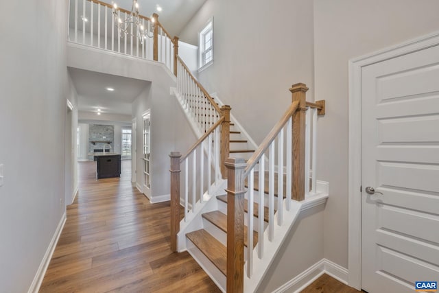 stairs with a notable chandelier, wood finished floors, and baseboards