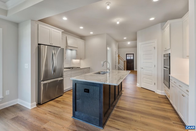 kitchen with white cabinets, light wood-style floors, appliances with stainless steel finishes, and a sink