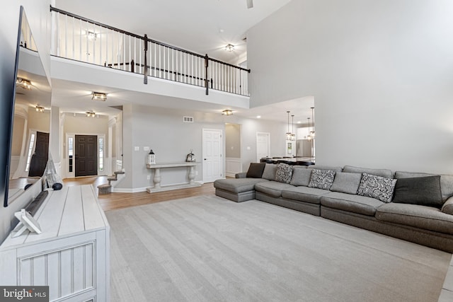 living room featuring visible vents, a high ceiling, and light wood-style floors