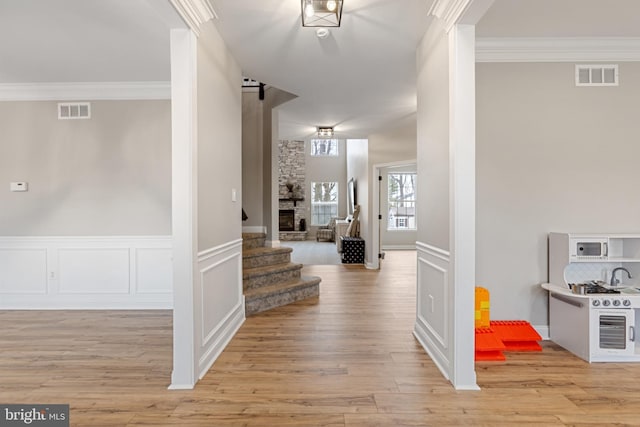 hall featuring visible vents, crown molding, and light wood-style floors