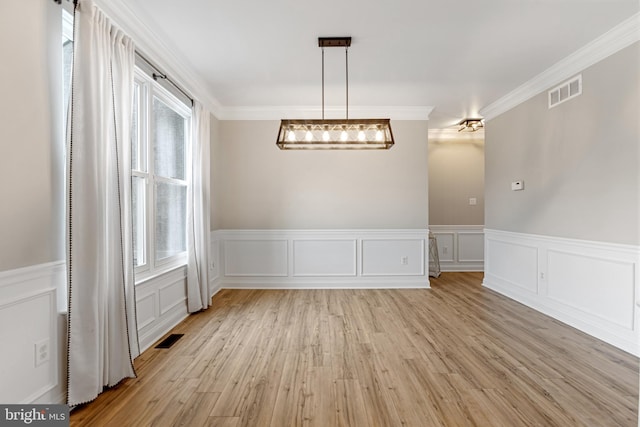 unfurnished dining area featuring light wood finished floors, visible vents, and crown molding