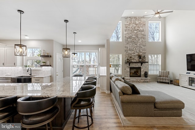 kitchen featuring tasteful backsplash, open floor plan, light stone counters, a fireplace, and a sink