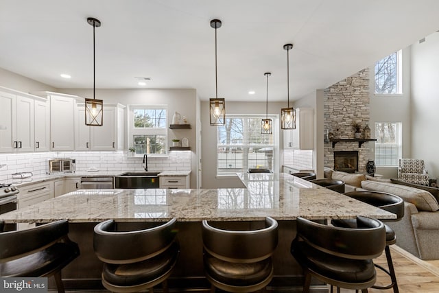 kitchen featuring a breakfast bar, open floor plan, white cabinetry, light wood finished floors, and decorative backsplash